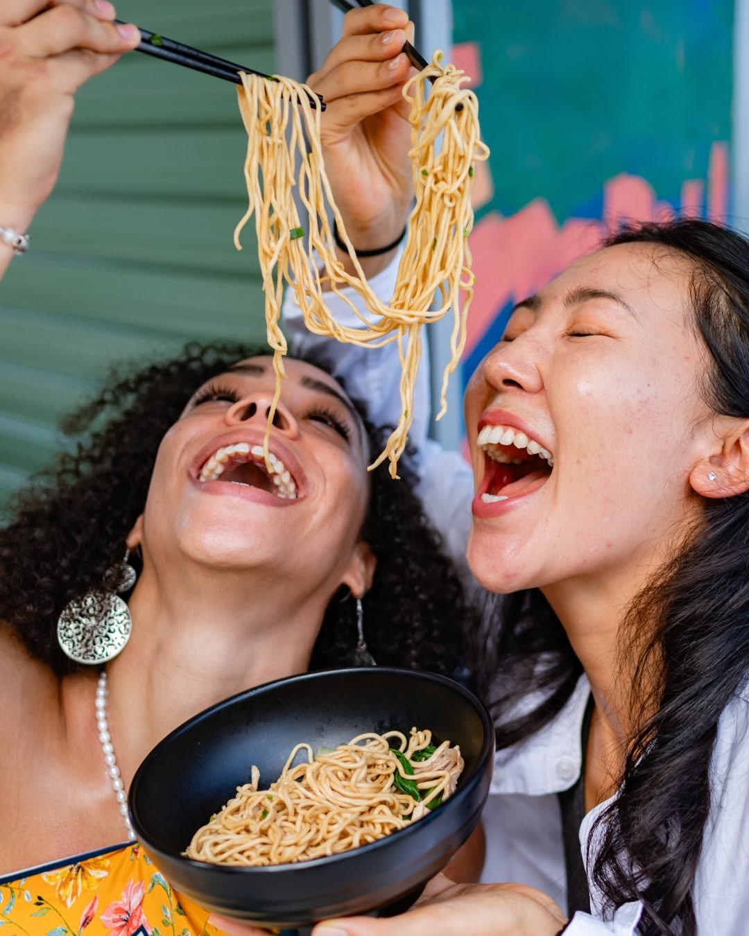 Two friends sharing noodles